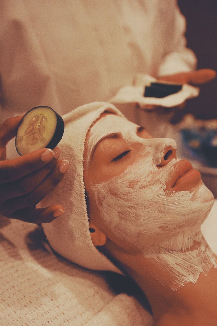 Serene spa treatment capturing a woman enjoying a facial with cream mask and cucumber slices.