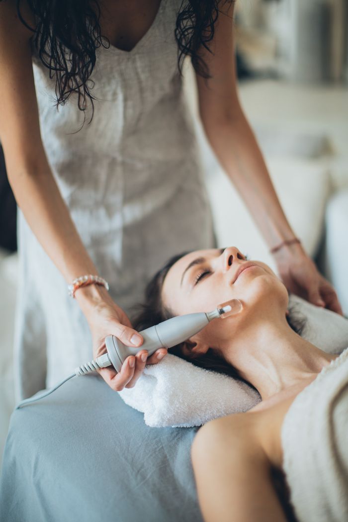 A woman enjoying a relaxing facial treatment using advanced technology at a spa. Perfect for wellness promotion.