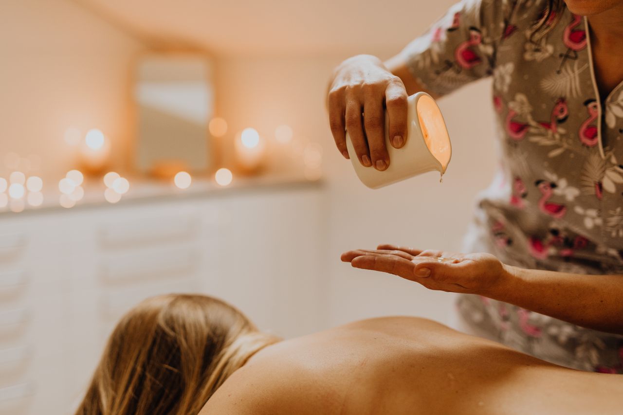 Professional spa therapist pouring soothing massage oil for a relaxing treatment.